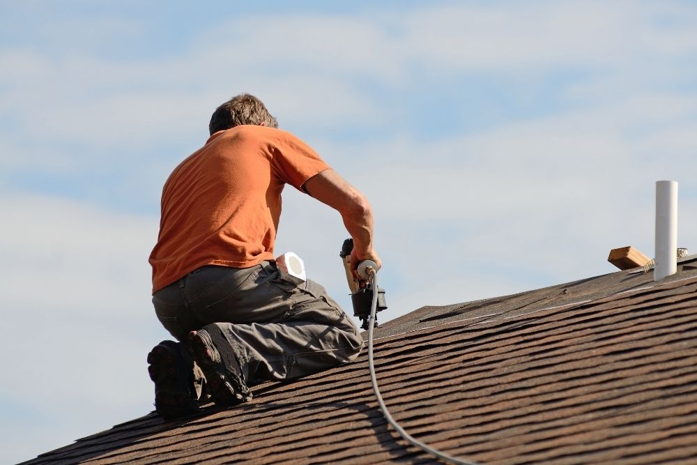 Guy on roof installing shingles